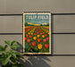 A metal sign with a colorful illustration of a tulip field, mounted on a wall.