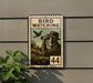 A vintage-style stamp-like sign with a birdwatcher illustration, mounted on a wall next to a plant.