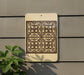 a decorative tile pattern on a wall, with a plant in the foreground.