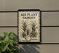 a sign that reads "Air Plant Garden Forever" with a black and white illustration of a plant on it. The sign is mounted on a wall, and there is a plant to the left of the sign.