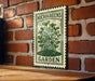 A metal sign with a green border and a drawing of a plant is mounted on a brick wall.