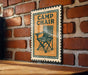 A metal sign with a picture of a folding chair is mounted on a brick wall.