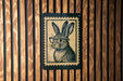 A wooden wall with a framed image of a rabbit wearing glasses.