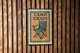 A sign with the word "CAMP CHAIR" on it is displayed on a wooden wall.