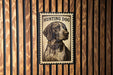A metal sign with a dog illustration and the text "HUNTING DOG" is displayed on a wooden wall.