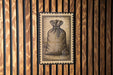 a wooden wall with a framed illustration of a bag, which appears to be a postage stamp-like design.