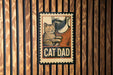 A metal sign with a cat and a man's face, mounted on a wooden wall.