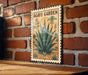 A vintage-style sign for the "Agave Garden" is displayed on a brick wall, featuring an illustration of an agave plant.