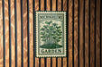 A metal sign with a green and white design, featuring a plant illustration, is mounted on a wooden wall.