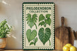 a green and white sign with illustrations of various leaves, placed on a wooden surface next to a wooden cutting board and some potted plants.
