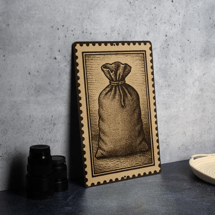a framed illustration of a bag, which is placed on a table next to some black camera lenses.