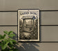 A garden swing sign is mounted on a wall, with a plant visible to the left.