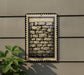 a brick wall with a decorative border, and there is a plant to the left of the brick wall.