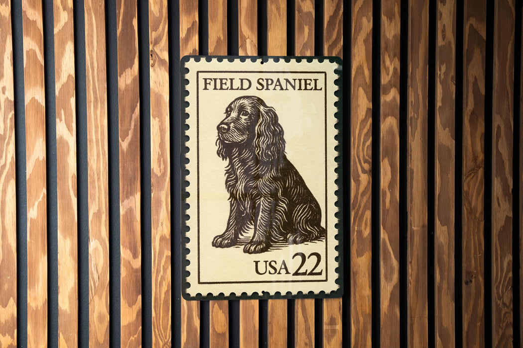 A Field Spaniel postage stamp from the United States, with the number 22 printed on it, is displayed on a wooden surface.
