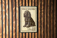 A Field Spaniel postage stamp from the United States, with the number 22 printed on it, is displayed on a wooden surface.