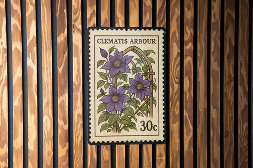 A postage stamp from Clematis Arbour, featuring a floral illustration of purple flowers, is displayed on a wooden wall.