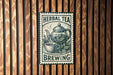 A sign for "Herbal Tea Brewing" is displayed on a wooden wall, featuring an illustration of a teapot and a cup of tea.