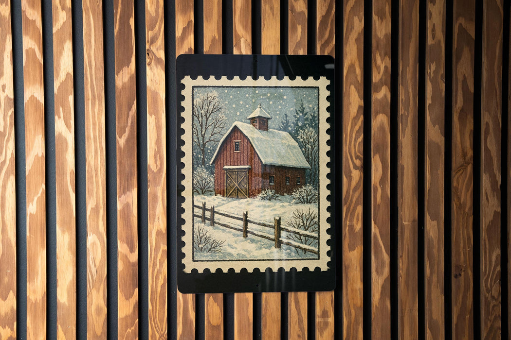 A framed painting of a red barn with a snow-covered roof is displayed on a wooden wall.