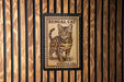 A wooden wall with a framed image of a Bengal cat, which appears to be a postage stamp.
