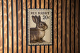 A 20 cent postage stamp featuring a rabbit is displayed on a wooden wall.