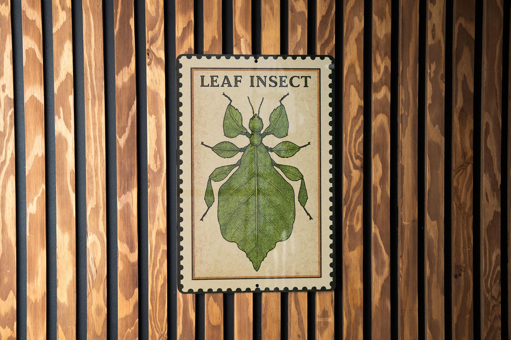 A metal sign with a leaf insect illustration is mounted on a wooden wall.