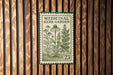 a green and white stamp-like sign with illustrations of plants and flowers, mounted on a wooden wall.