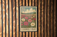 A vintage-style postage stamp depicting a field of colorful flowers, with the text "COSMOS FIELD" printed on it.