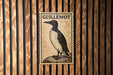 a postage stamp with a bird illustration, mounted on a wooden wall.
