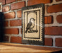 a wooden table with a framed print of a bird on a brick wall.