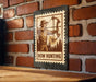 A metal sign with a bow and arrow illustration, mounted on a brick wall.