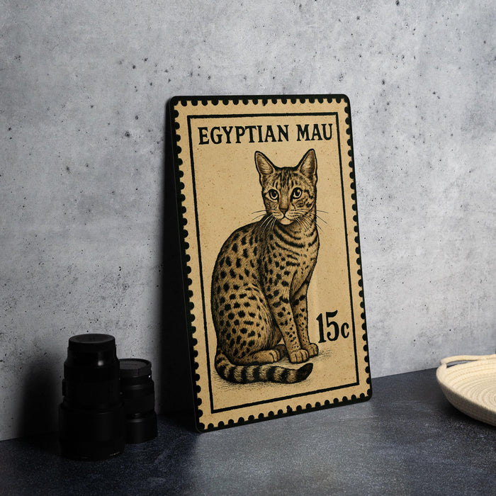 A metal plate with a printed illustration of a cat, which appears to be a postage stamp, is displayed on a table.