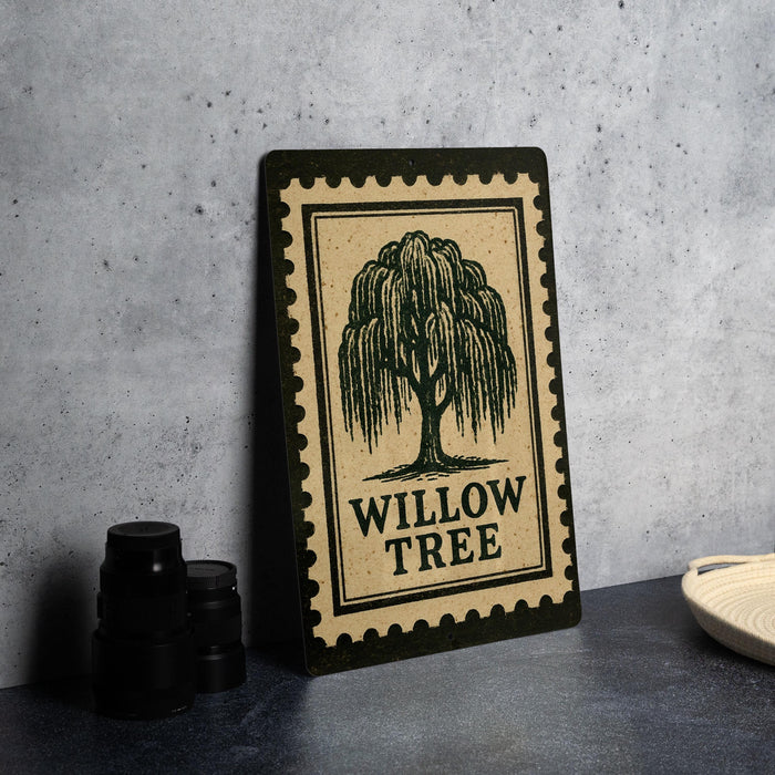 a framed poster with a willow tree illustration, placed on a table next to some black camera lenses.