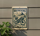 a sign with a bicycle and mountain scenery, mounted on a wall.