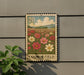a metal sign with a floral design, mounted on a wall next to a plant.