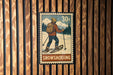 A vintage-style postage stamp depicting a person skiing on snowshoes, with the word "SNOWSHOEOING" written below the illustration.