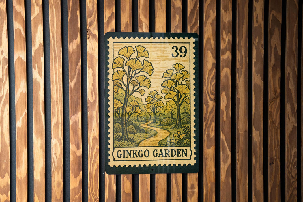 A postage stamp featuring a scenic landscape with a winding path and trees, mounted on a wooden wall.