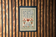 a cross-stitch pattern with the alphabet and numbers displayed on a wooden panel.