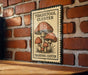 A metal sign with a mushroom illustration is mounted on a brick wall.
