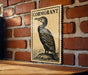 a wooden table with a framed illustration of a bird, specifically a cormorant, on the wall behind it.