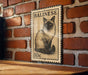 A metal sign featuring a cat illustration is mounted on a brick wall.