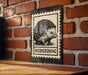 A metal sign featuring a black and white illustration of a hedgehog is mounted on a brick wall.
