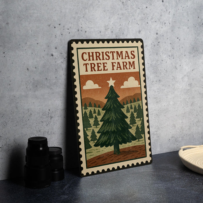 A Christmas tree farm sign with a pine tree illustration and a star on top, placed on a table next to some black camera lenses.