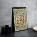 a cross-stitch embroidery of the alphabet on a wooden frame, placed on a table next to some black camera lenses.