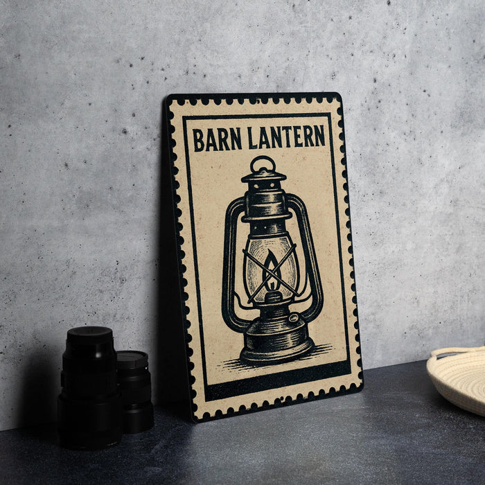 A metal sign with the word "Barn Lantern" on it, featuring an illustration of a lantern, is displayed on a table next to some black camera lenses.
