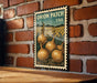 A vintage-style metal stamp featuring an illustration of onions growing in a field, mounted on a brick wall.