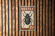 A vintage-style 25¢ postage stamp featuring a detailed illustration of a beetle.
