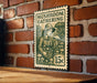 A metal sign with a stamp-like design hangs on a brick wall, featuring an illustration of a person holding mushrooms and the text "MUSHROOM GATHERING".