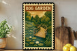 A vintage-style metal sign with a curved wooden bridge and lily pads, surrounded by a lush green forest and a clear sky, is displayed on a wooden shelf.