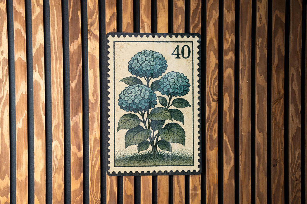A vintage-style postage stamp featuring a blue hydrangea flower is displayed on a wooden wall.