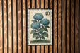 A vintage-style postage stamp featuring a blue hydrangea flower is displayed on a wooden wall.